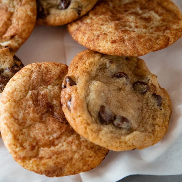 Close-up of freshly baked chocolate chip and snickerdoodle cookies on white parchment paper.